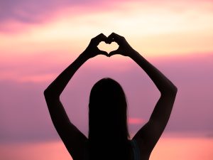 silhouette of girl making heart with hands
